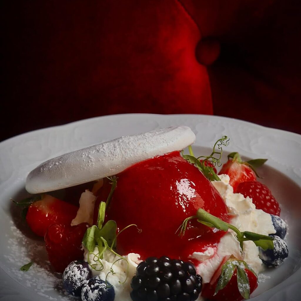 Pavlova aux fruits rouges et eau de rose servie sur lit de crème fouettée, dessert raffiné chez Eva Restaurant à Lille centre.