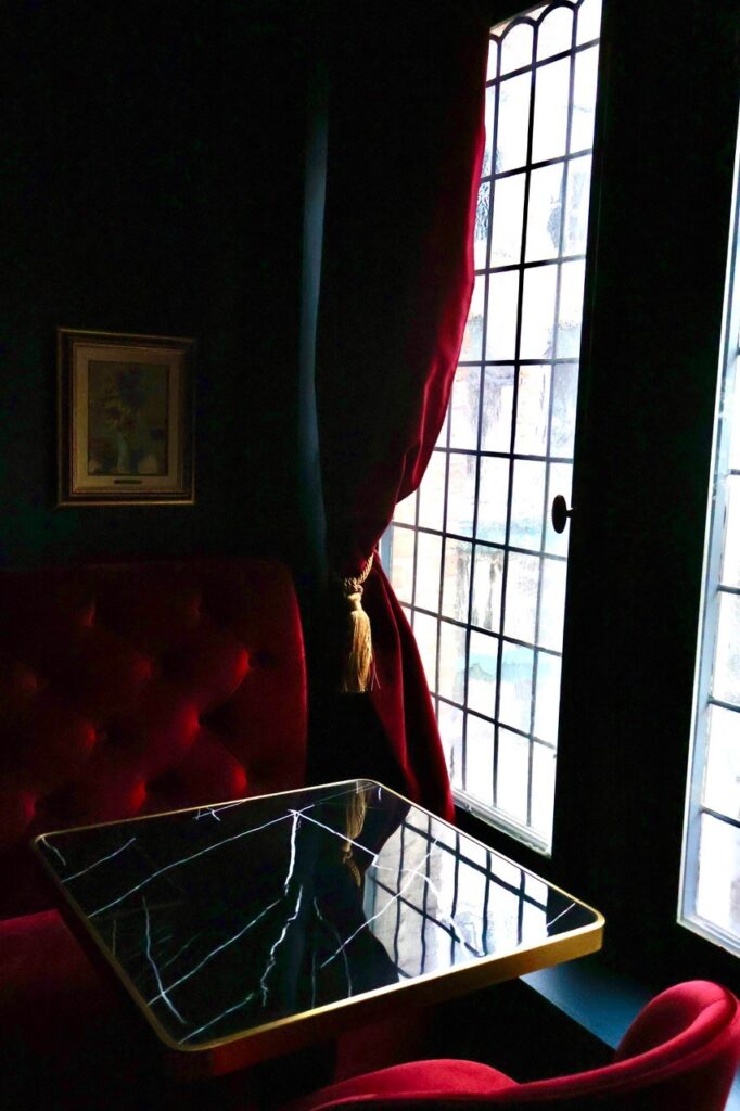 Table en marbre noir près d’une fenêtre à vitraux dans l’ambiance feutrée d’Eva Restaurant, restaurant chic à Lille Grand-Place.